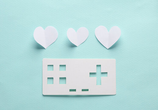 Paper retro gamepad icon with hearts on blue background. Paper art