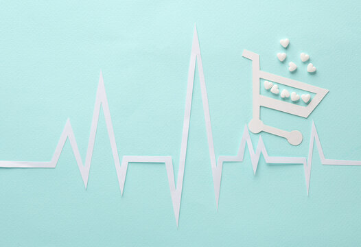 Healthy heart concept. Paper-cut heart rhythm cardiogram with shopping trolley and heart-shaped pills on a gray background. Creative medicine layout - Powered by Adobe