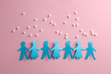 Fototapeta na wymiar Paper cut chain of people and heart shaped pills on pink background