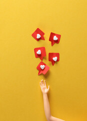 Doll's hand with Social media likes on yellow background. Creative minimal layout