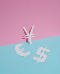 Obraz premium Different signs of currencies cut out of paper on a blue-pink background