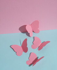 Butterflies cut out of paper on a blue-pink pastel background. Creative minimal layout.