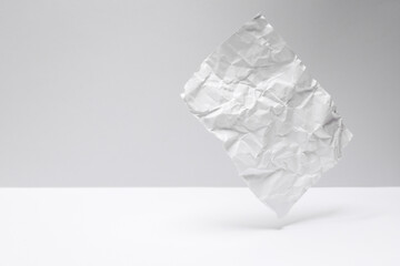 Crumpled sheet of paper levitating on a gray-white background