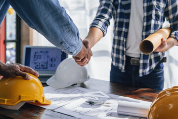 Engineers consulting team close up to design building blueprints paper for clients with building models to work at office.