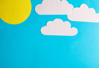 Paper cut clouds with sun on blue background