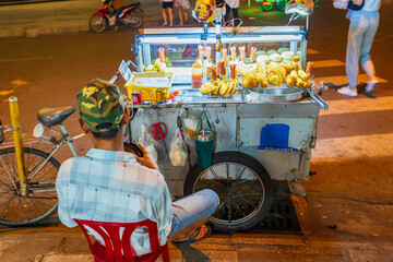 A street vendor sitting behind his stall selling food after dark at Nha Trang in Vietnam