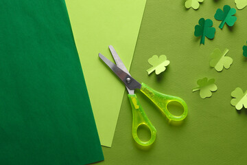 Paper art. Paper-cut clover leaves and scissors on a green background. St.Patrick 's Day