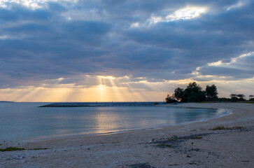 沖縄県名護市の海岸ビーチの雲と夕日の光のカーテン