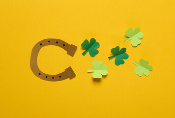 St.Patrick 's Day. Paper horseshoe with clover leaves on yellow background. March 17. Hand made, Paper art. Flat lay Top view