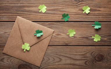 St. patrick's day invitation. Envelope with clover leaves on wooden background. Flat lay