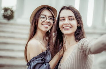 Two young women take a selfie together and have fun in the city.