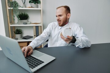A man in a wheelchair, a businessman with tattoos in the office at a laptop, a coffee break, annoyance, the concept of working a person with disabilities, freedom from social frames