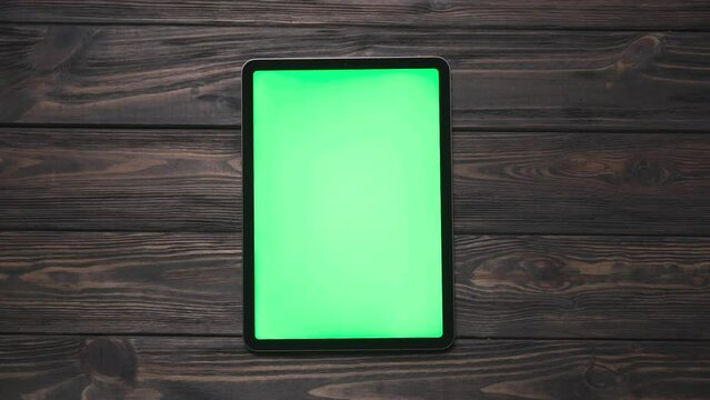 tablet computer with a green screen on a wooden background.
