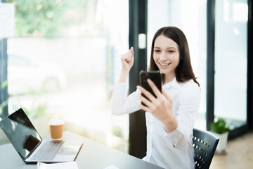 Excited businesswoman using mobile phone while in office.