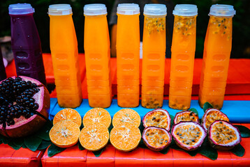 Bottles of freshly squeezed orange juice and passion fruit juice. Sliced ​​fruit in the...
