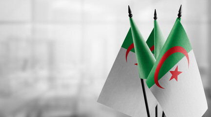 Small flags of the Algeria on an abstract blurry background