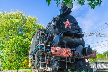 An old steam locomotive is standing on a siding. Wheels and drive of an old steel locomotive. An old black steam locomotive is standing on the rails.