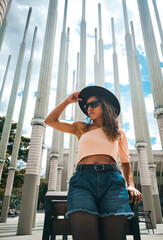 brunette woman in hat seen from below in the city
