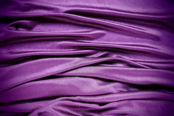 Fototapeta na wymiar Velour fabric, similar to silk. Textiles in a folds and beautiful waves. Purple, pink, magenta shades on the drapery. Sewing material for evening dresses, furniture upholstery, curtains and interior.