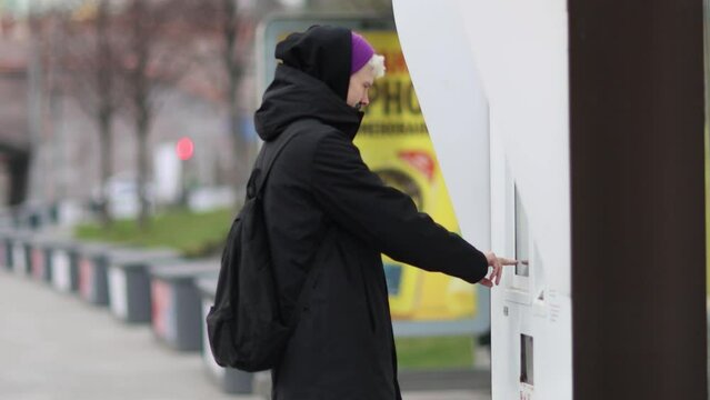 Male passenger analyzes transport card at a public transportation stop. Checking map and waiting for transport in city. Public transport route