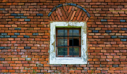 old weathered brick wall with barred window,