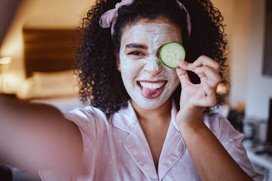 Selfie, portrait and cucumber for skincare by woman, happy and emoji, fun and silly while grooming, mask or facial. Face, fruit and girl with tongue out for photo, beauty or routine with eco product