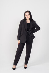 A young brunette poses standing on a white background / The girl is dressed in a strict business suit, there is a lot of space around the model for