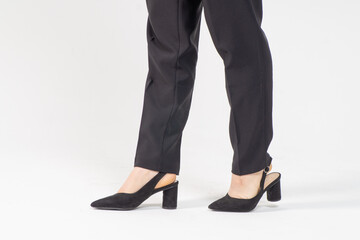 Female legs in strict business black trousers and high-heeled shoes close-up on a white background...