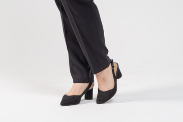 Female legs in strict business black trousers and high-heeled shoes close-up on a white background / Business woman concept