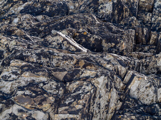A geological strata as a background. Stone texture, full frame. Brown and gray rock formation