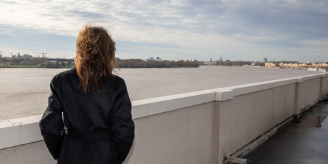 brunette woman in raincoat looking view of river garonne in Bordeaux city Gironde
