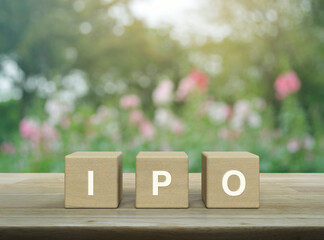 IPO letter on wood block cubes on wooden table over blur pink flower and tree in park, Initial...
