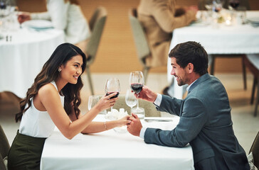 Love, wine and toast with a couple in a restaurant for their anniversary celebration or romantic dinner. Night, glasses or dates with a young man and woman celebrating an event together with a cheers