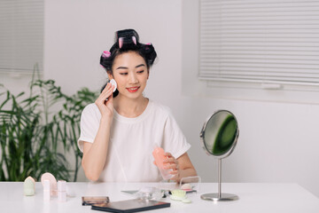 Beauty Routine. Attractive young female applying makeup removal milk on cotton pad while standing near mirror