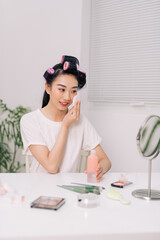 Young happy woman removing makeup from her face enjoying her skin and smiling at the mirror