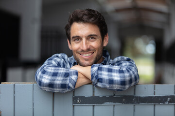 farm worker leaning on a stable