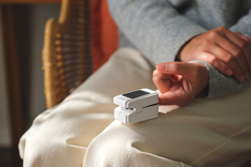 Closeup image of a woman using digital fingertip pulse oximeter device to measure oxygen and blood pulse rate