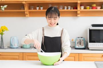 キッチンで料理をしている若い女性