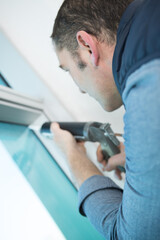 man using a silicone gun to repair a window