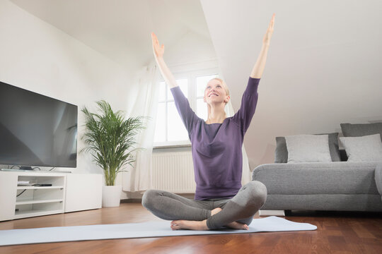 Young woman doing yoga on exercise mat in living room, Bavaria, Germany