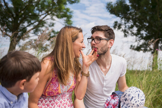 Couple eating raspberries from fingers on meadow in the countryside, Bavaria, Germany