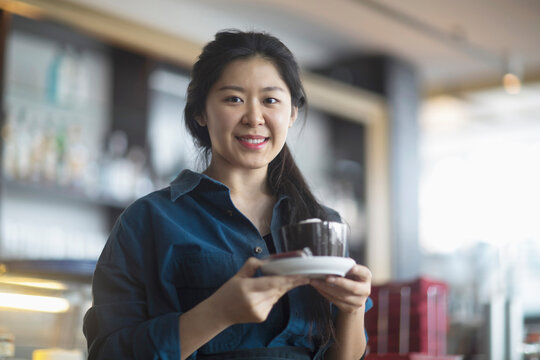 Portrait of a young waitress serving coffee in coffee shop, Freiburg Im Breisgau, Baden-württemberg, Germany