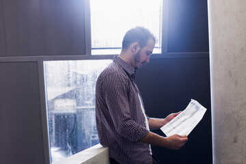 Young architect looking at blueprint in an office,Freiburg im Breisgau, Baden-Württemberg, Germany