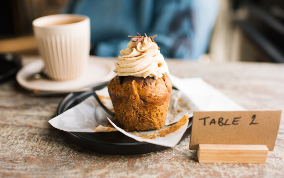 unwrapped cupcake on a table in a cafe with coffee