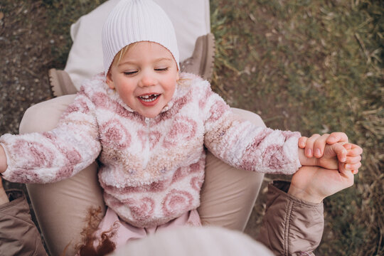 Toothless baby girl in her mother's arms outoors in cold weather