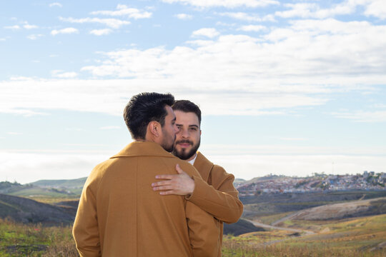 portrait of gay caucasian man hugging his latino boyfriend in mountain