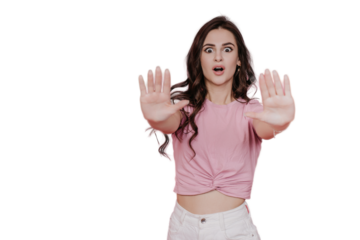 Brunette shocked young woman in pink t-shirt with wide opened eyes pulling hands to camera makes stop gesture, stands against transparent background. Don’t pass by. Mockup, discount, sale.
