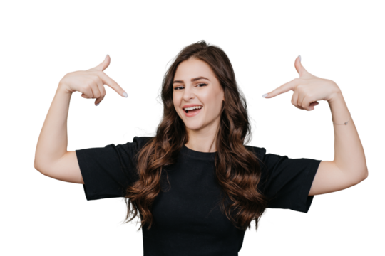 Attractive brunette young woman with wavy long hair points at herself by index fingers, looks at camera, toothy smiles over transparent background. Italian girl satisfied by healthy lifestyle. Blogger