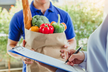 Food Delivery concept. Asian woman hand accepting bag of food, fruit, vegetable delivery from professional deliveryman Postman and express grocery delivery.