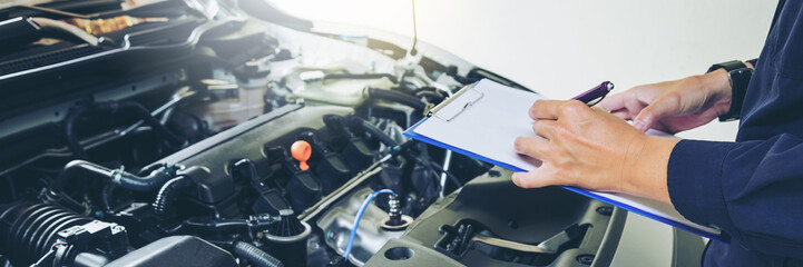 mechanic holding a clipboard of service order working in garage. Repair service.